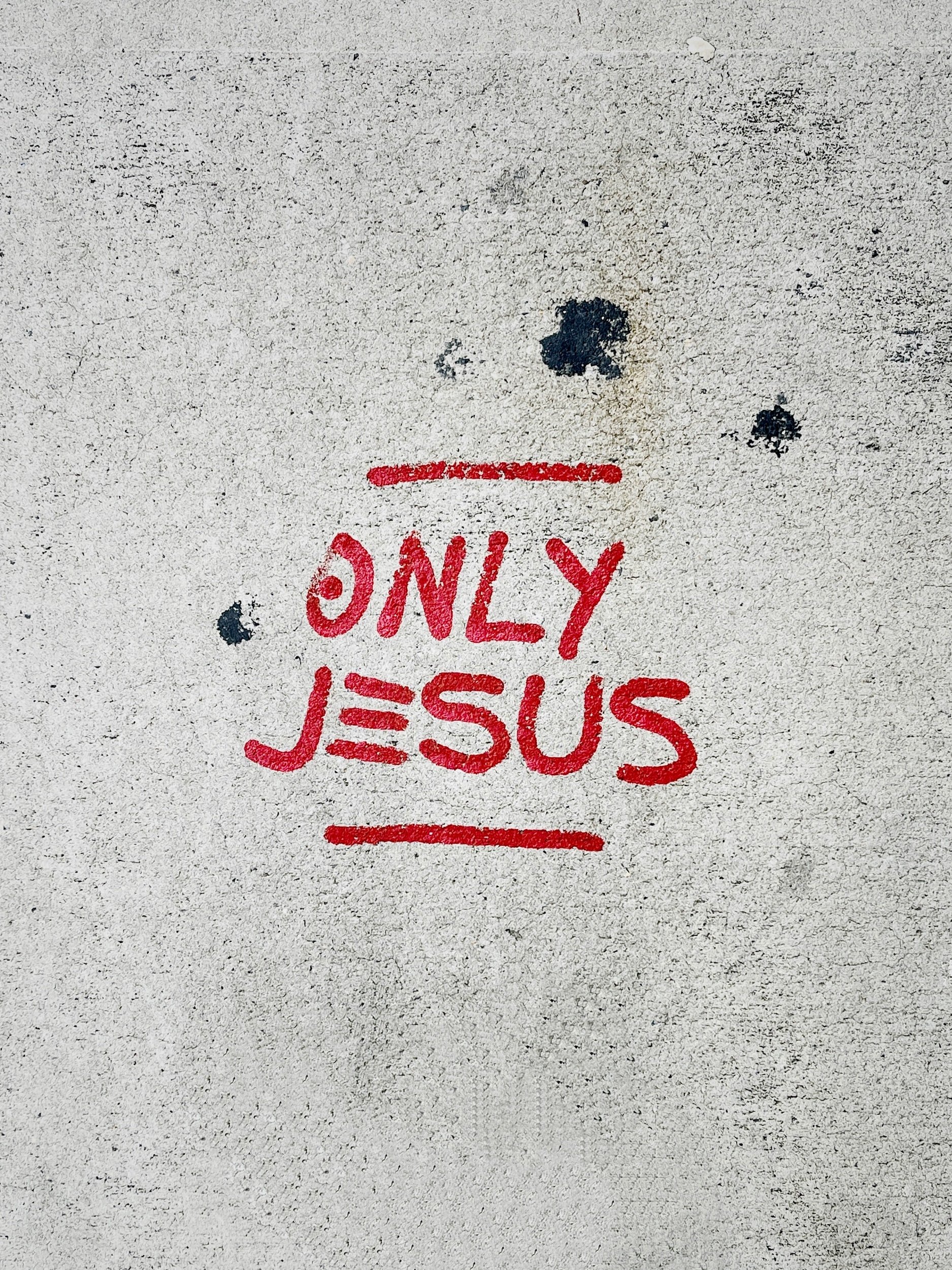 Only Jesus in red spray paint on concrete